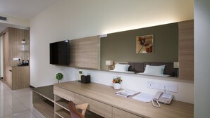A modern hotel room with a wooden desk, a flat-screen TV, a telephone, and a small plant. - One Pacific Hotel & Serviced Apartments (George Town)