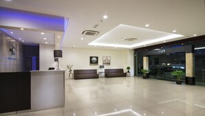 A modern hotel lobby with a reception desk, seating area, and a glass door entrance. - One Pacific Hotel & Serviced Apartments (George Town)