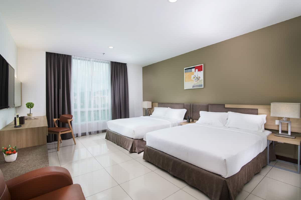 Habitación de hotel con dos camas, un escritorio, una silla, un televisor y una ventana con cortinas.