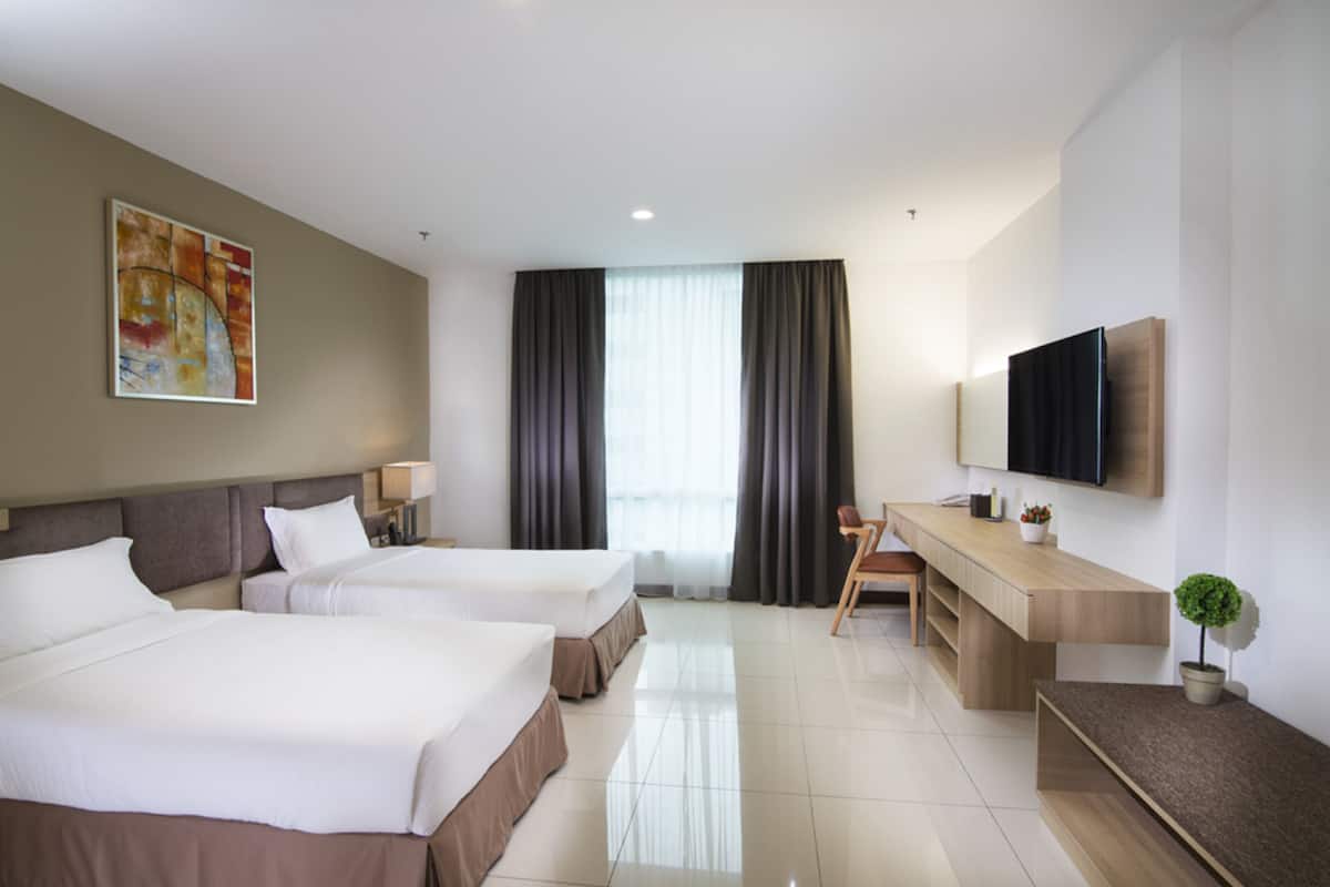Habitación de hotel con dos camas, un escritorio, una silla, un televisor y un cuadro en la pared.