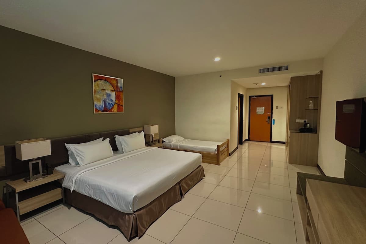 Habitación de hotel con dos camas individuales, una cama grande, televisión, escritorio y un cuadro en la pared.