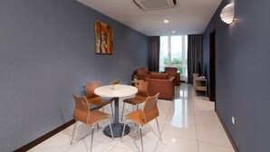 A modern hotel room with a dining area, a sofa set, and a large window with curtains. - One Pacific Hotel & Serviced Apartments (George Town)