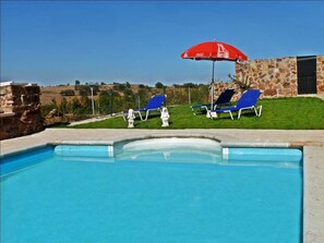 Una piscina al aire libre de temporada, sombrillas, tumbonas