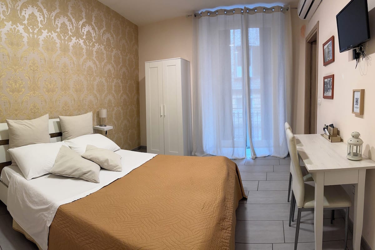 Une chambre d’hôtel comprenant un lit, une table de chevet, une lampe, une armoire et un bureau avec une chaise.