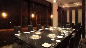 A conference room with a long table, chairs, and a glass partition.