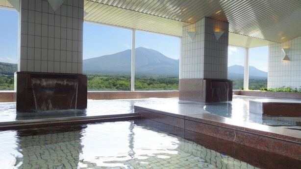 A modern indoor pool area with tiled flooring, large windows, and a view of a mountain.