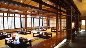 A traditional Japanese-style room with tatami mat flooring, low wooden tables, and sliding doors.