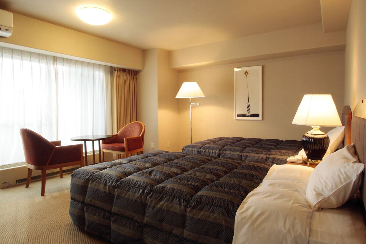 Een hotelkamer met een groot bed, een bureau, een stoel en twee bedlampen.