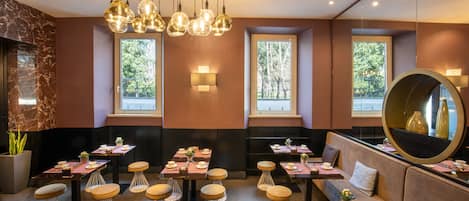 A modern restaurant with round tables, bar stools, and a large mirror.
