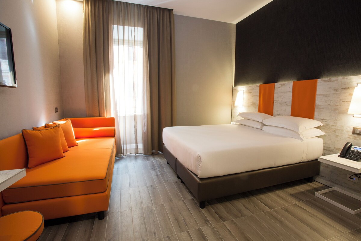 Una habitación de hotel con cama, sofá, escritorio y teléfono.