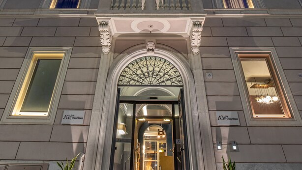 A grand building with a symmetrical facade, large windows, and a central entrance with a decorative arch. - The Guardian Hotel (Rome)