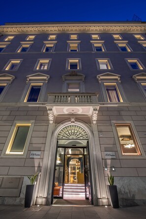 Un edificio imponente con fachada simétrica, amplias ventanas y una entrada central con arco decorativo.