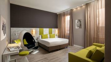 Una habitación de hotel moderna con una cama grande, un escritorio con una silla, un sofá y un ventanal con cortinas.