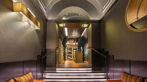 A modern hotel lobby with a staircase leading to the upper floor, featuring a reception desk, seating area, and a view of the interior. - The Guardian Hotel (Rome)