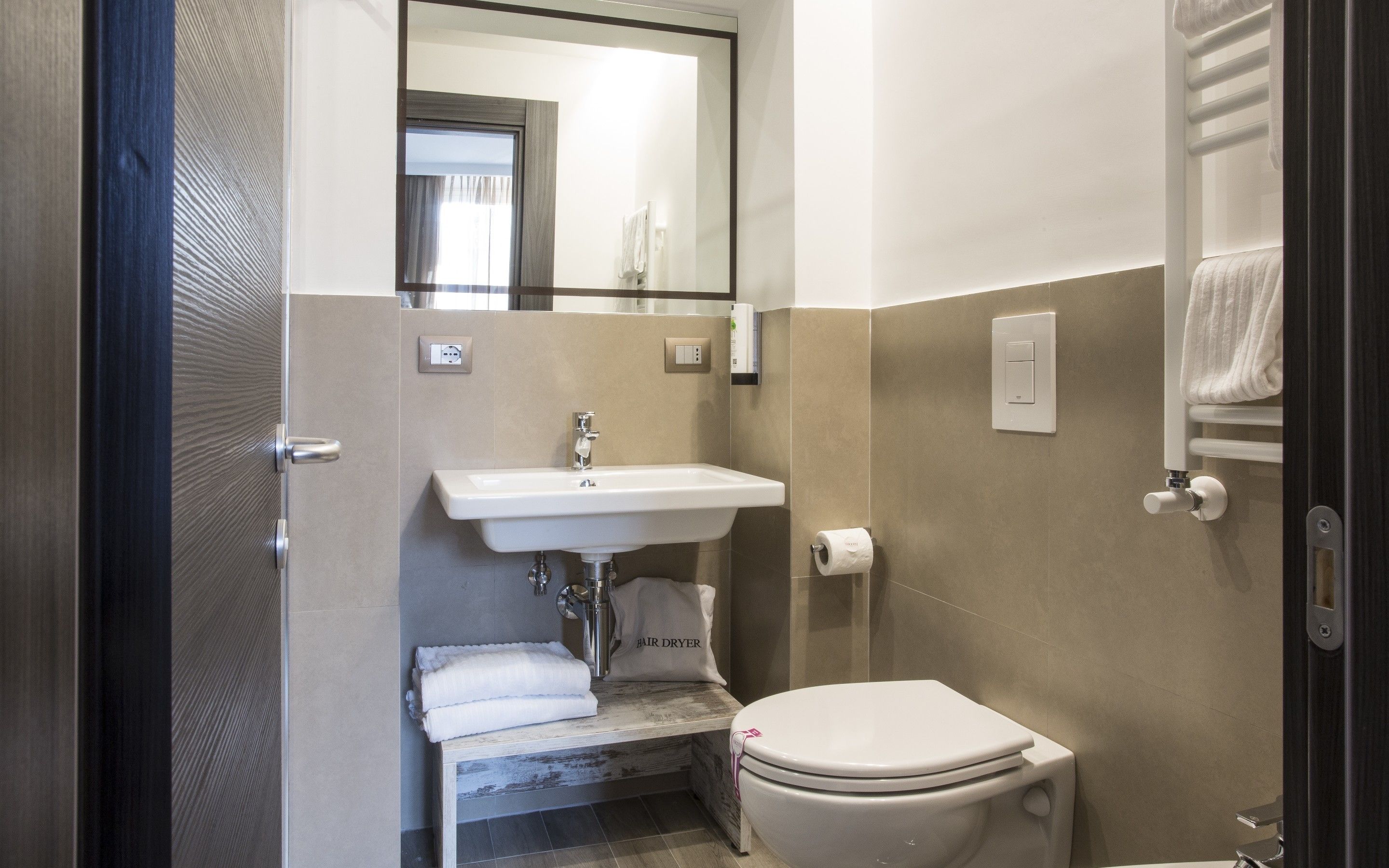 A compact bathroom with a sink, toilet, and a towel rack.