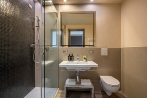 Une salle de bain moderne avec une douche à parois de verre, un lavabo blanc avec un miroir au-dessus et des toilettes.