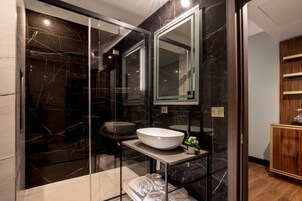 Un bagno moderno con uno specchio grande, un lavabo a incasso bianco e una cabina doccia in vetro.