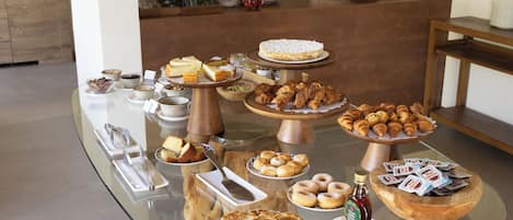 A buffet with various food items including pastries, cakes, and beverages.