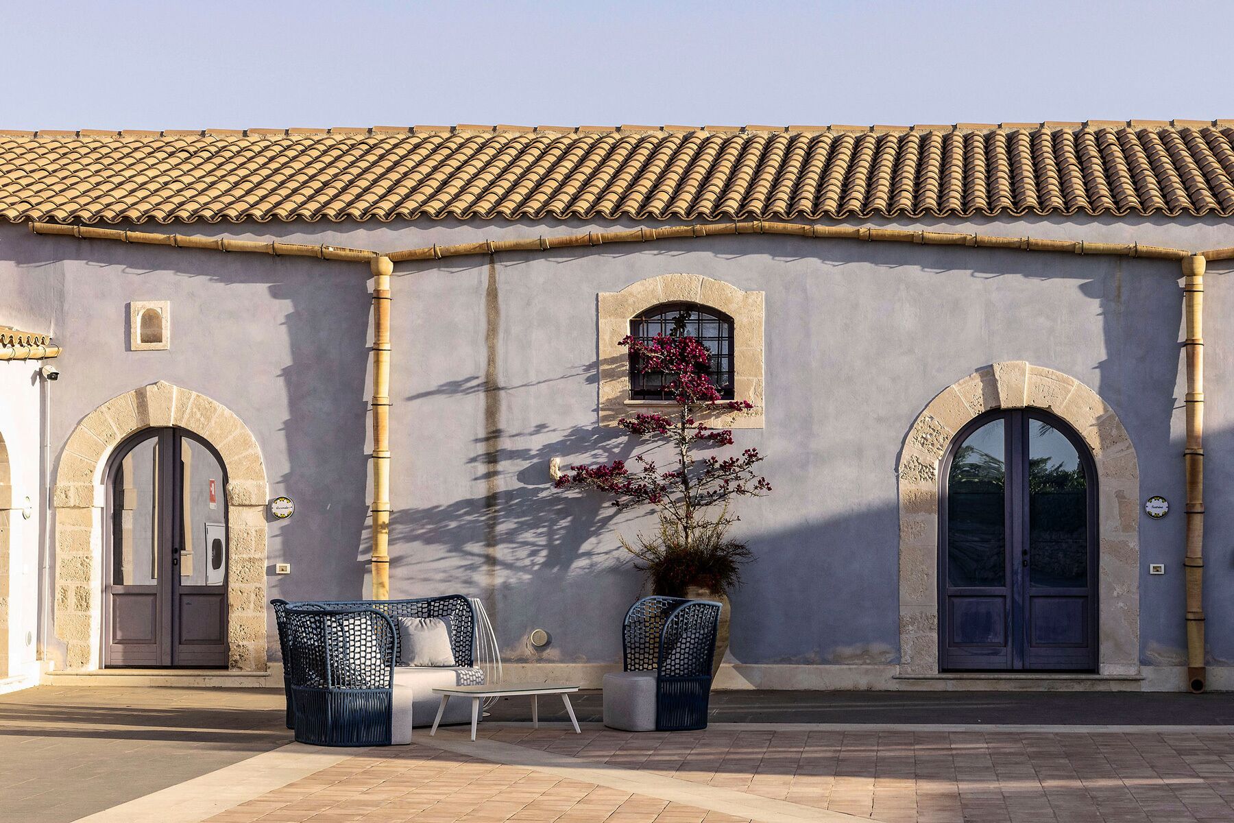 A building with a tiled roof, two arched doors, and a window with a flower box.