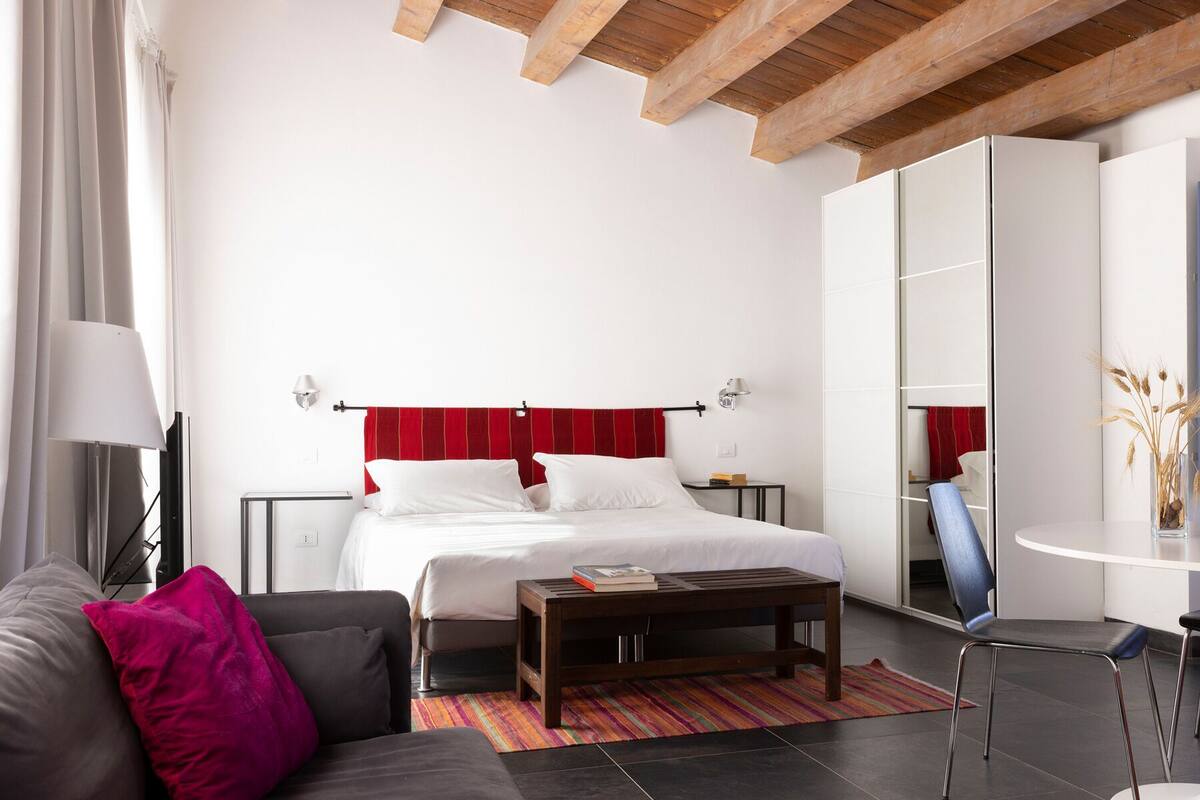 Quarto moderno com cama, sofá, mesa de centro e guarda-roupa.