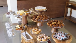 Un bufé con diversas opciones de pastelería, tartas y bebidas.