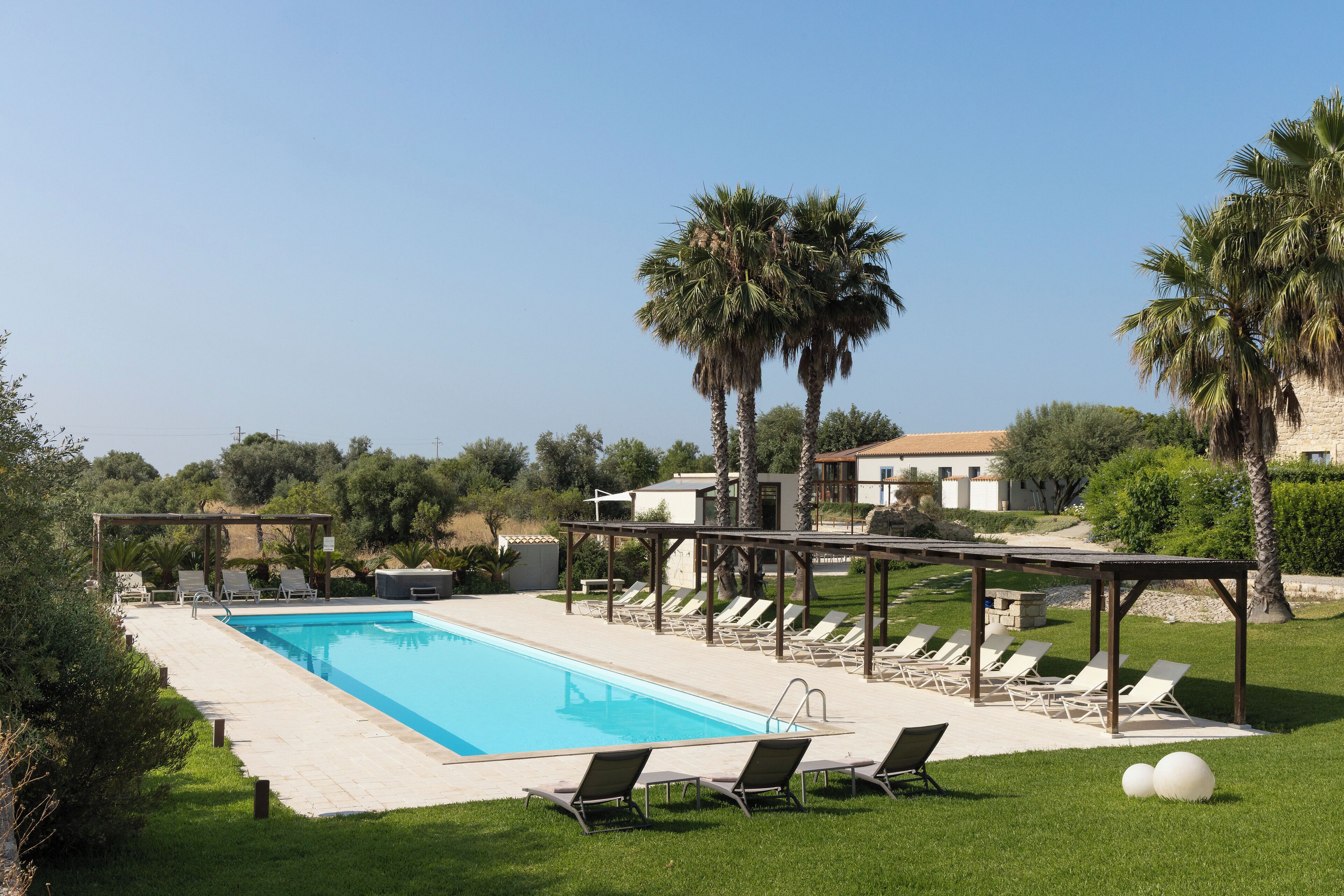 A swimming pool with lounge chairs and palm trees.