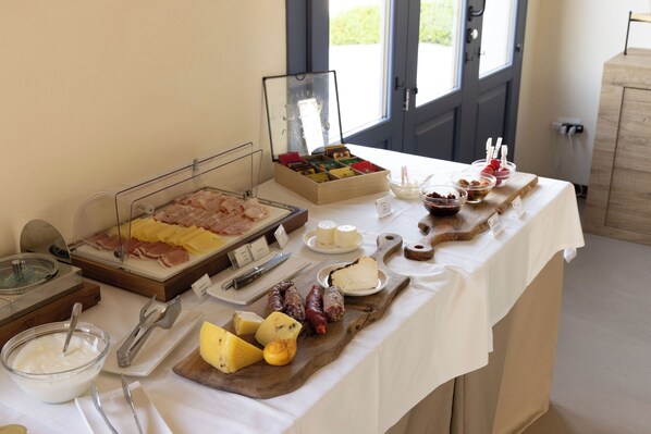 Una mesa de buffet con varios quesos, embutidos y condimentos.