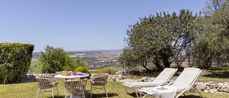 Una terraza con mesa y sillas, sillones de descanso y vistas a un paisaje urbano.