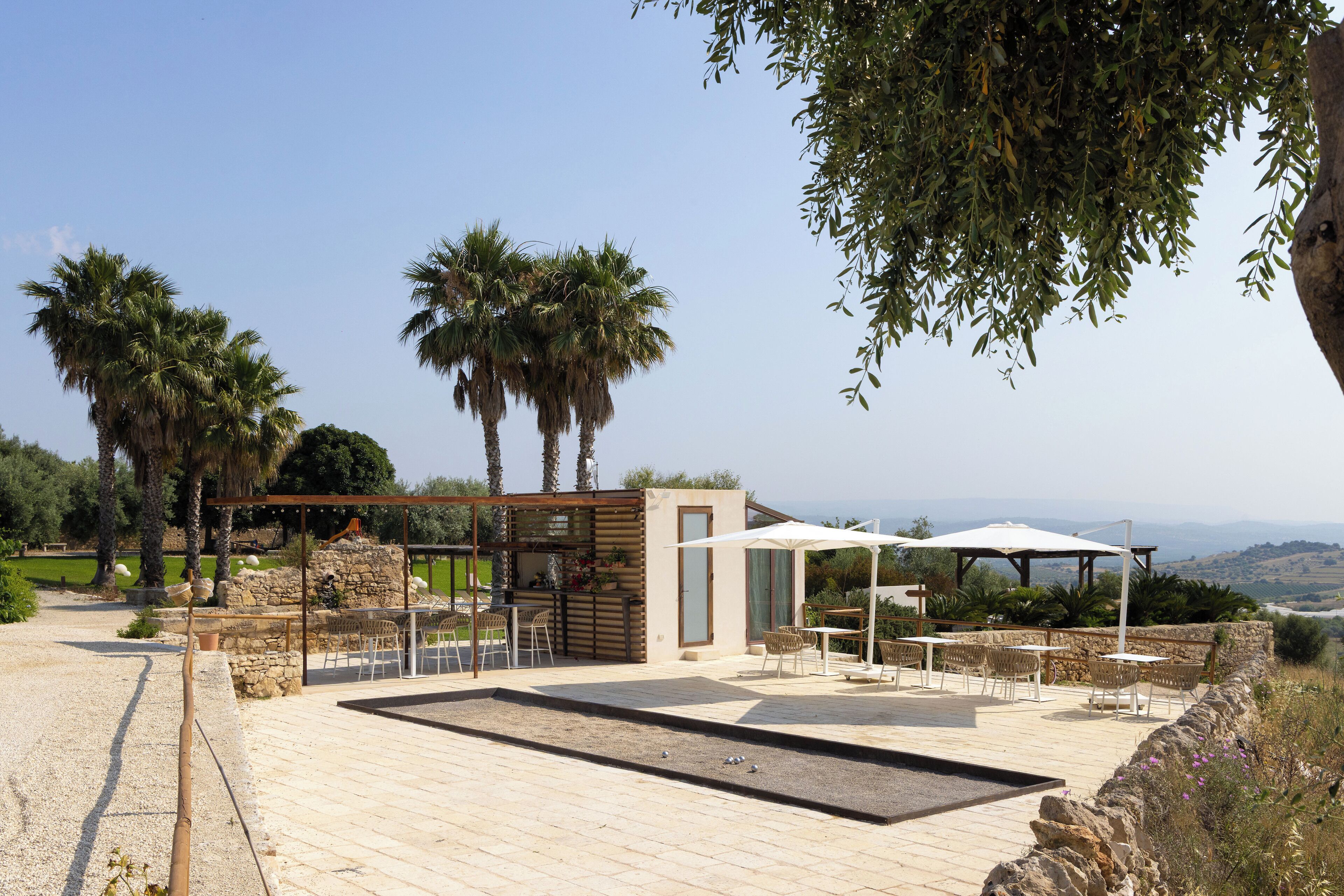 A patio area with outdoor seating, a stone wall, and a view of the landscape.