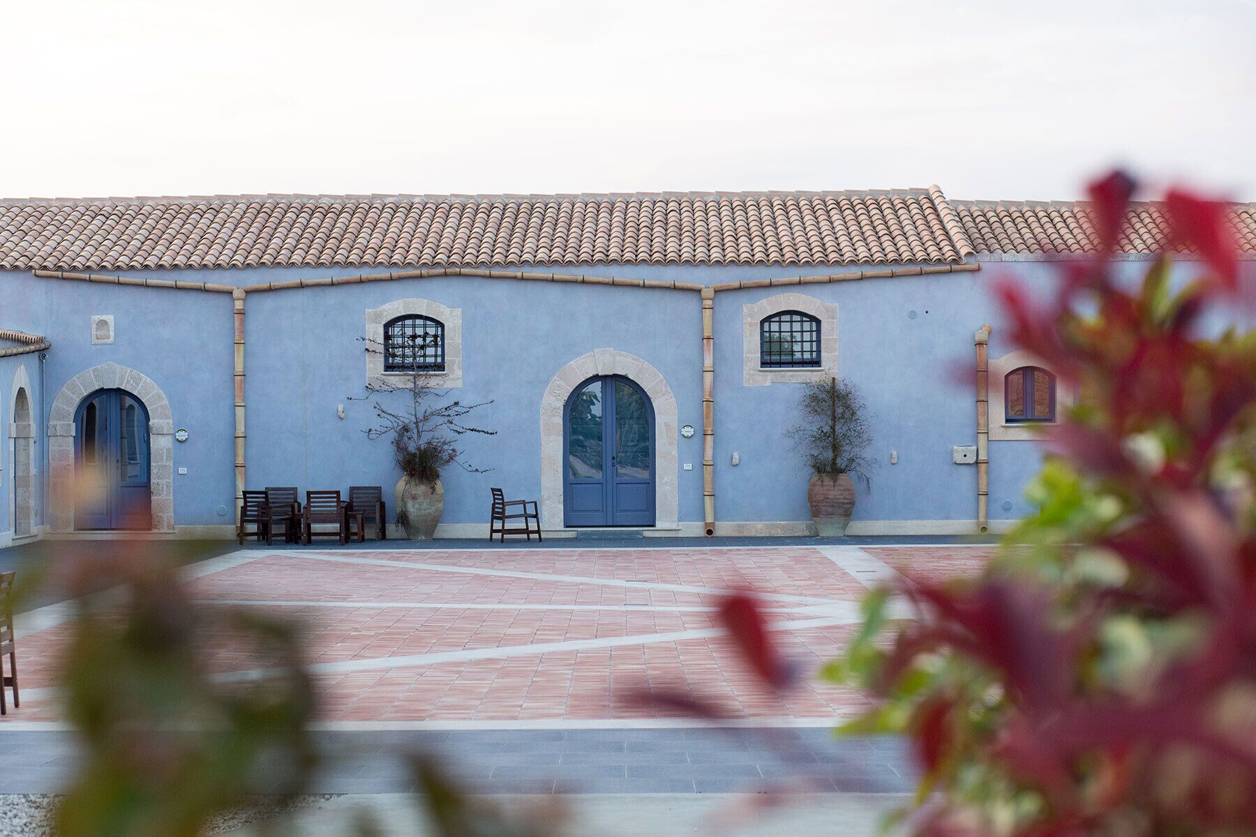 A building with a tiled roof, arched doorways, and a courtyard with benches.