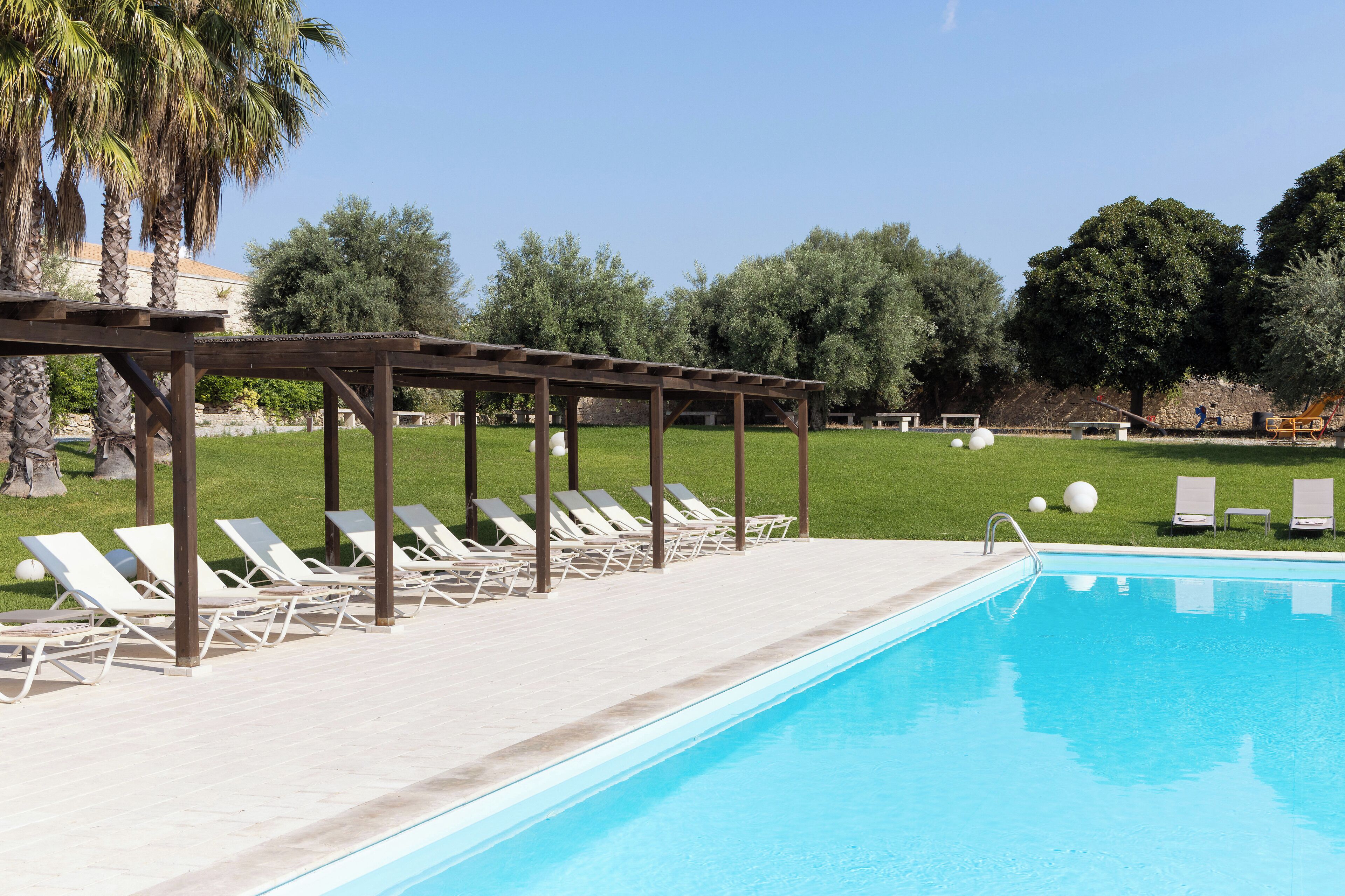 A swimming pool with lounge chairs and a pergola.