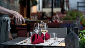 A person pouring wine into glasses on a table with a napkin and a fork. - Hôtel Castillan (La Grave)