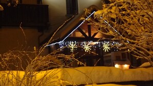A building with the sign "Hôtel CASTILLAN" at night, surrounded by snow-covered branches and illuminated by string lights. - Hôtel Castillan (La Grave)