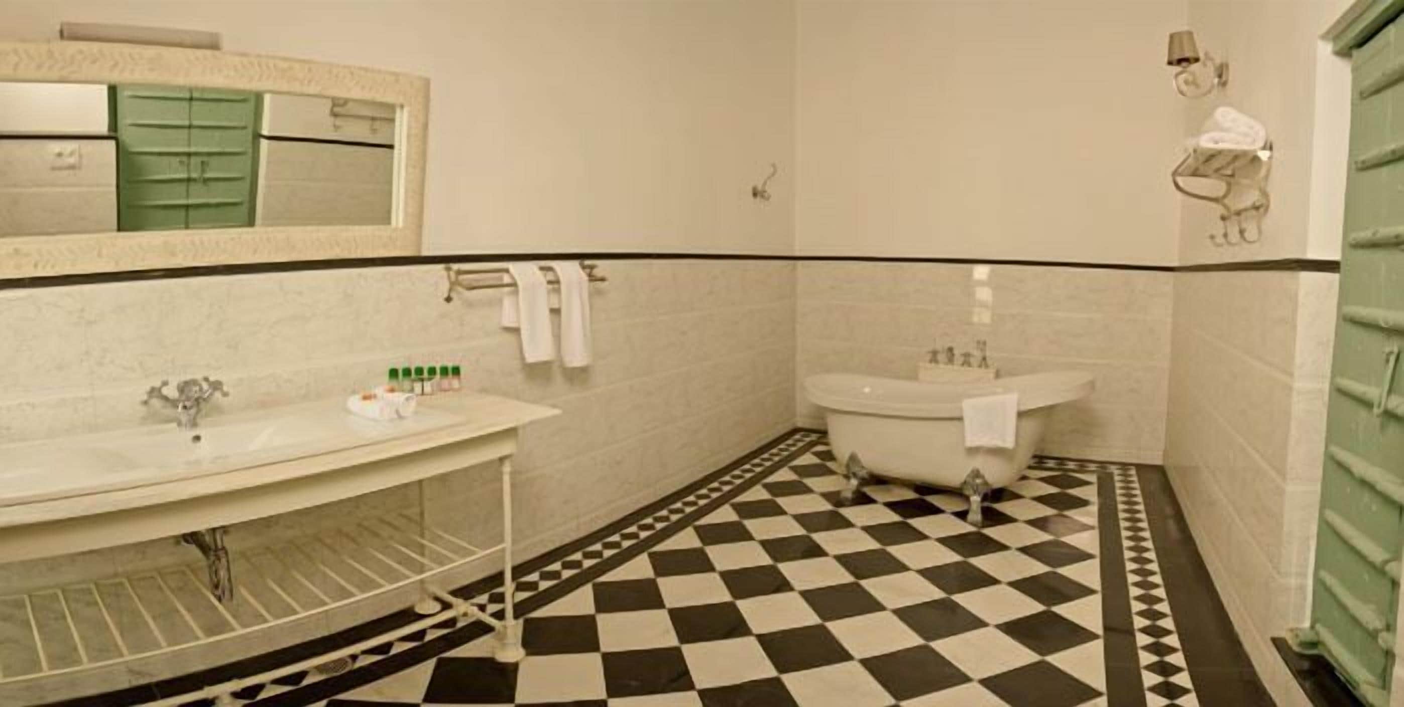 A bathroom with a checkered floor, a sink, a bathtub, and a mirror.