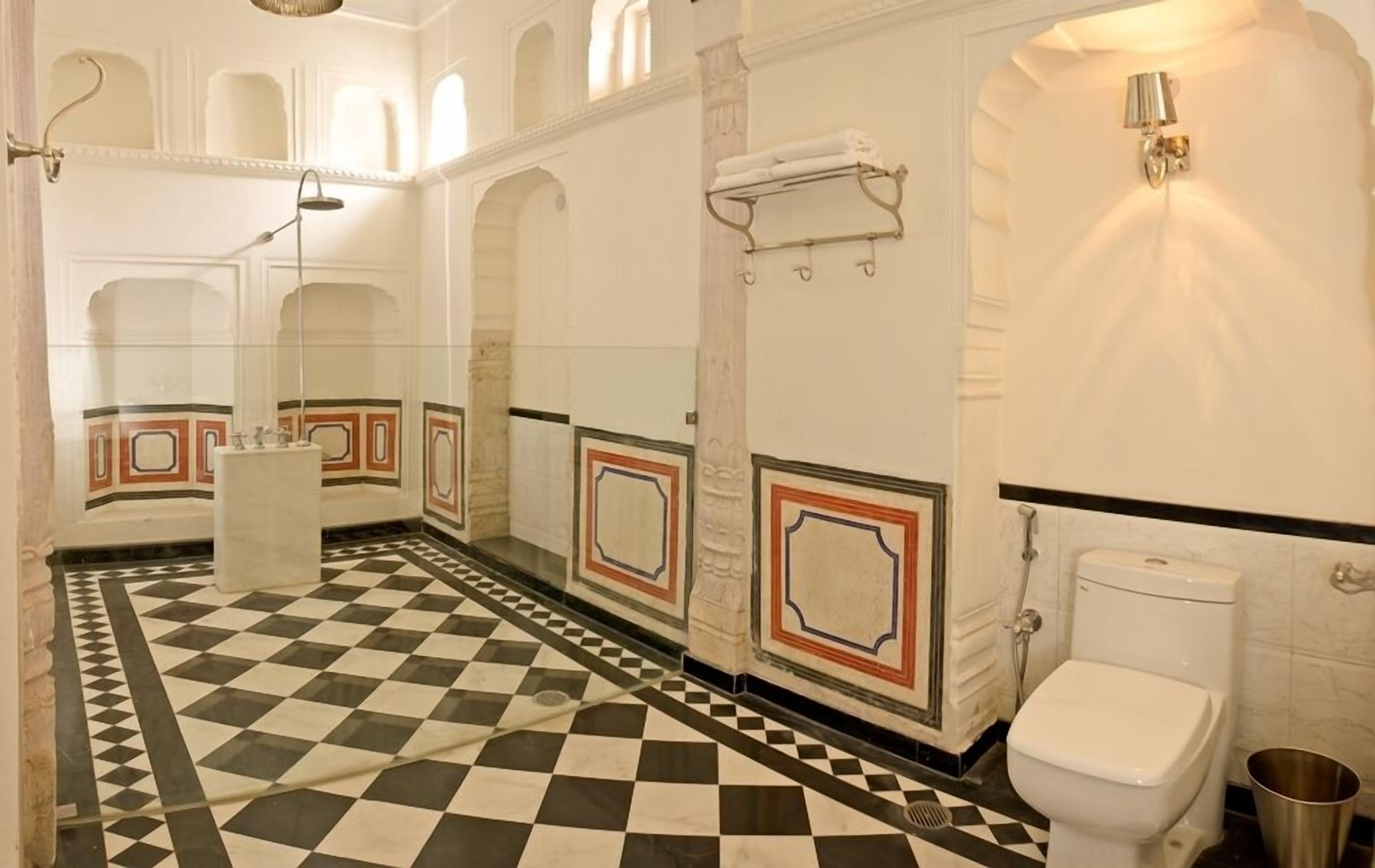 A bathroom with a checkered floor, a toilet, a sink, and a shower.