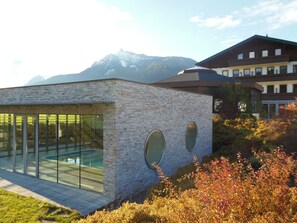 A modern building with large glass windows and a stone facade, surrounded by autumn foliage and a mountain in the background. - Berghof Mitterberg (Mitterberg-Sankt Martin)