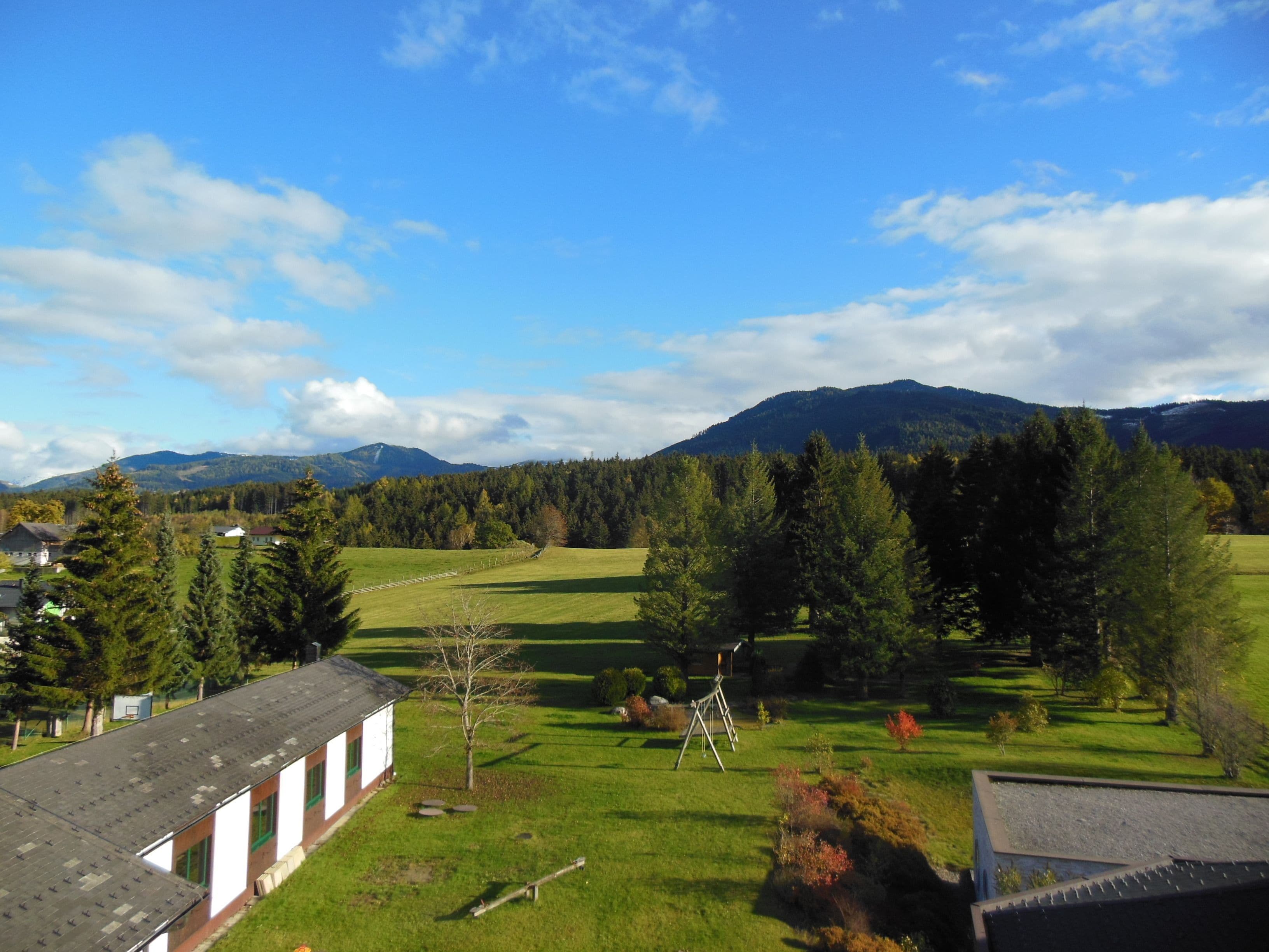 A rural landscape with a building featuring a sloped roof and a small garden area.