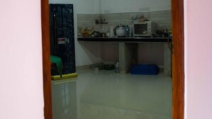 A kitchen with a refrigerator, microwave, and various kitchen items on the counter. - Sameera Villa (Weligama)