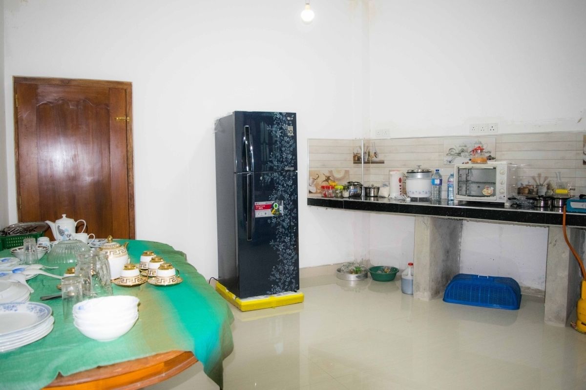 A kitchen with a refrigerator, microwave, and various kitchen items.