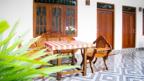A dining area with a checkered tablecloth, wooden chairs, and a large window with decorative glass panels. - Sameera Villa (Weligama)