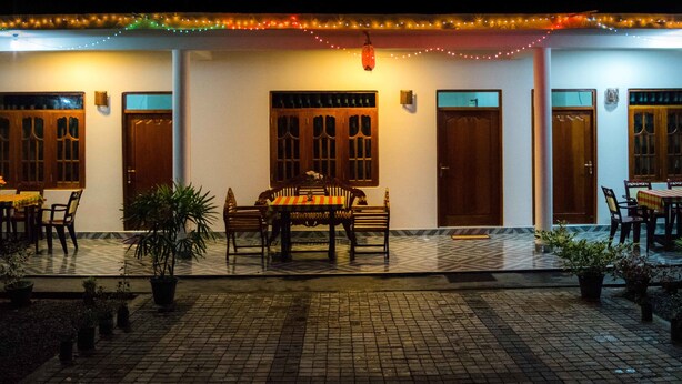 A restaurant with outdoor seating, wooden tables, and chairs, surrounded by potted plants. - Sameera Villa (Weligama)
