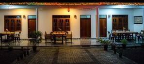 A restaurant with outdoor seating, wooden tables, and chairs, surrounded by potted plants. - Sameera Villa (Weligama)
