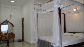 A bedroom with a four-poster bed, a wooden dresser, and a mirror. - Sameera Villa (Weligama)