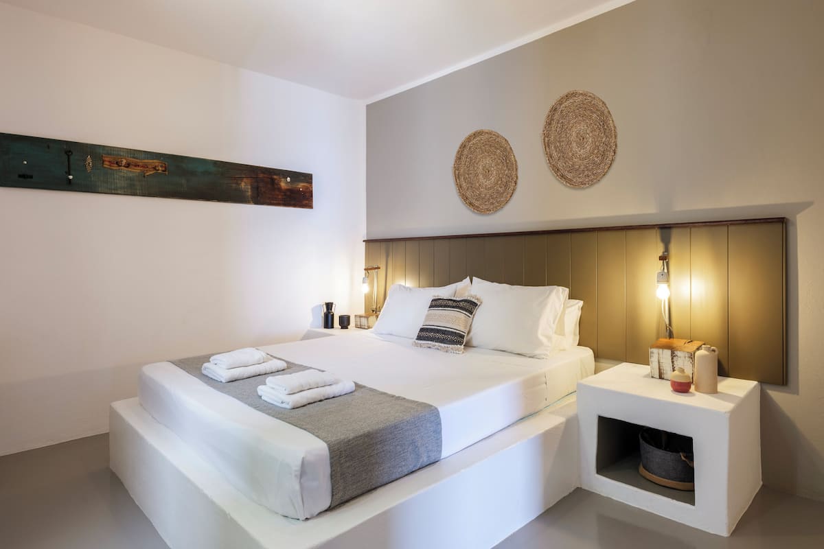 Una camera da letto moderna con un letto grande, comodini, una lampada a parete e una cuccia per animali domestici.
