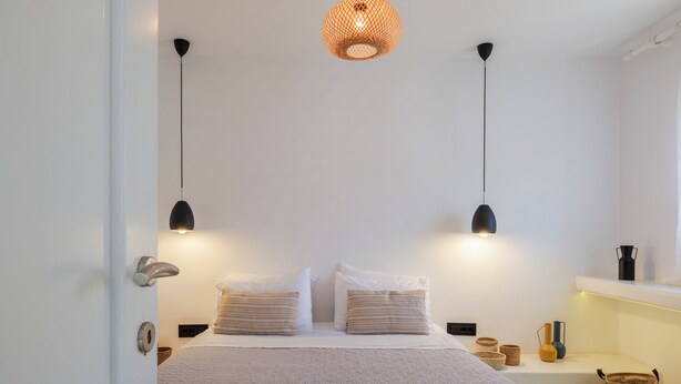 Un lit bien fait avec deux oreillers, une table de chevet avec une lampe et un luminaire suspendu au-dessus.