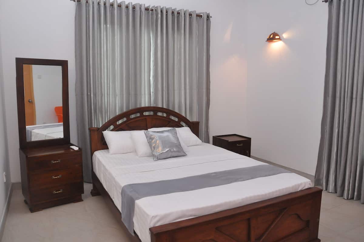 A neatly made bed with a wooden headboard, a bedside table, a nightstand, and a wall-mounted light fixture.