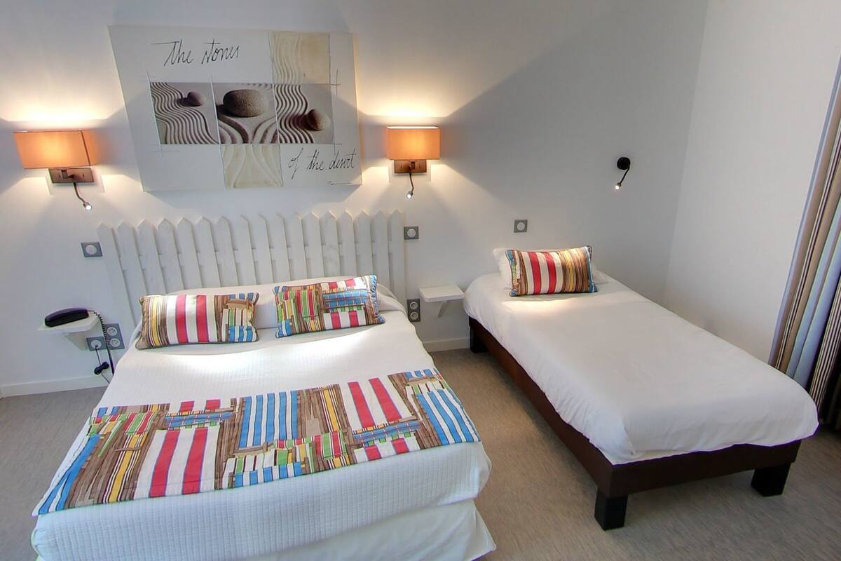 A hotel room with a large bed, two bedside tables, a telephone, and a wall-mounted artwork.