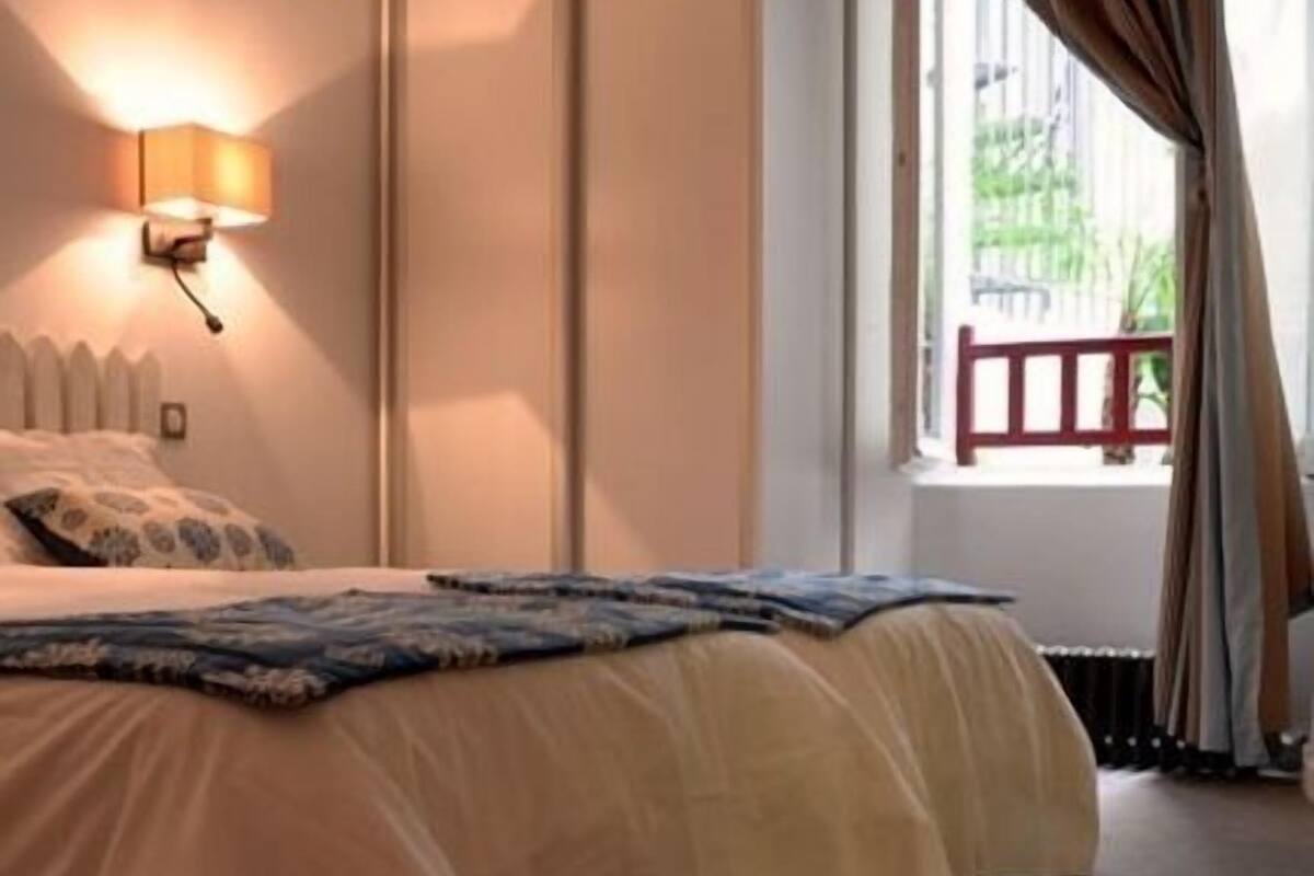 A bedroom with a bed, a nightstand, a lamp, and a window with curtains.