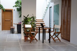 Un interior moderno con una mesa y sillas de madera, una planta en maceta y una escalera.