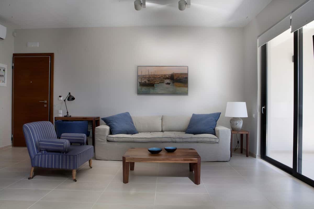 Un soggiorno con divano, poltrona, tavolino e un quadro appeso al muro.